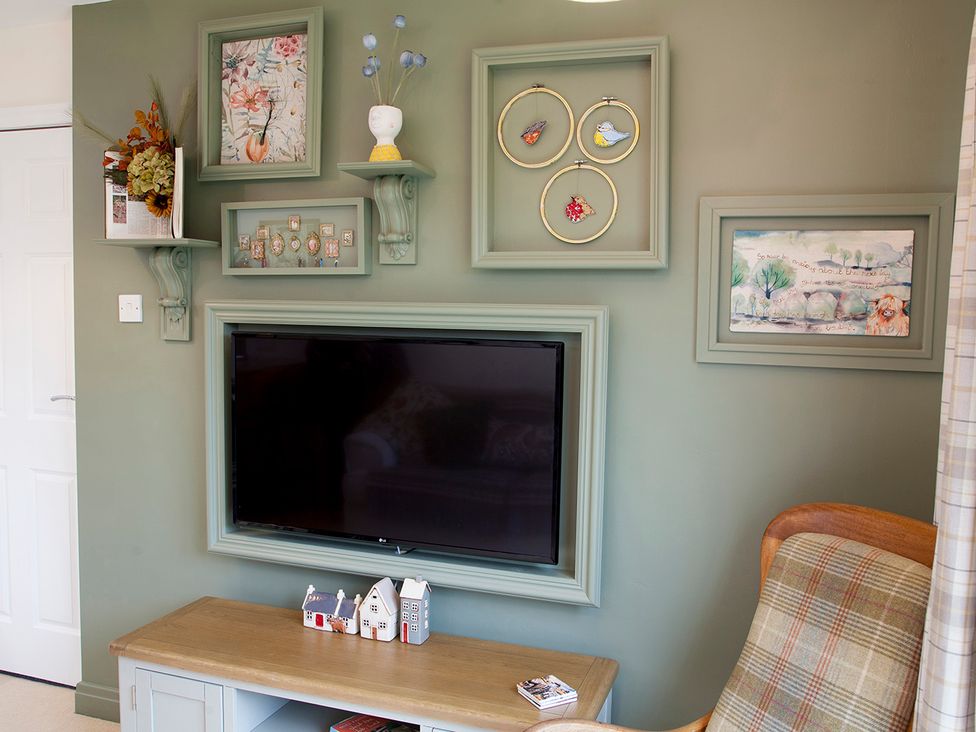 A living room with a television and decorative shelves at Snug Cottage in Honley