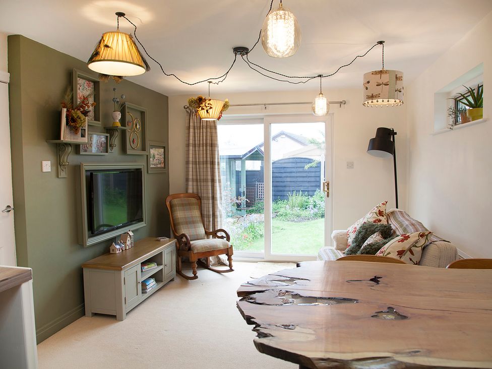 A living room with a sliding door and a rocking chair at Snug Cottage in Honley