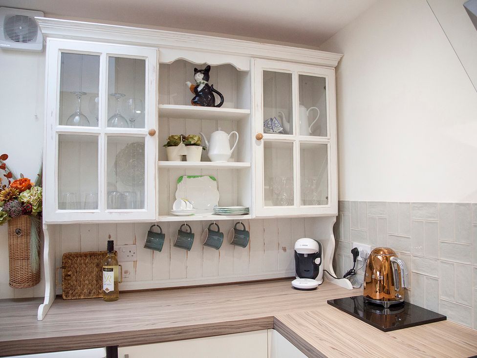 A kitchen featuring a cabinet with glassware and a kettle at Snug Cottage Honley