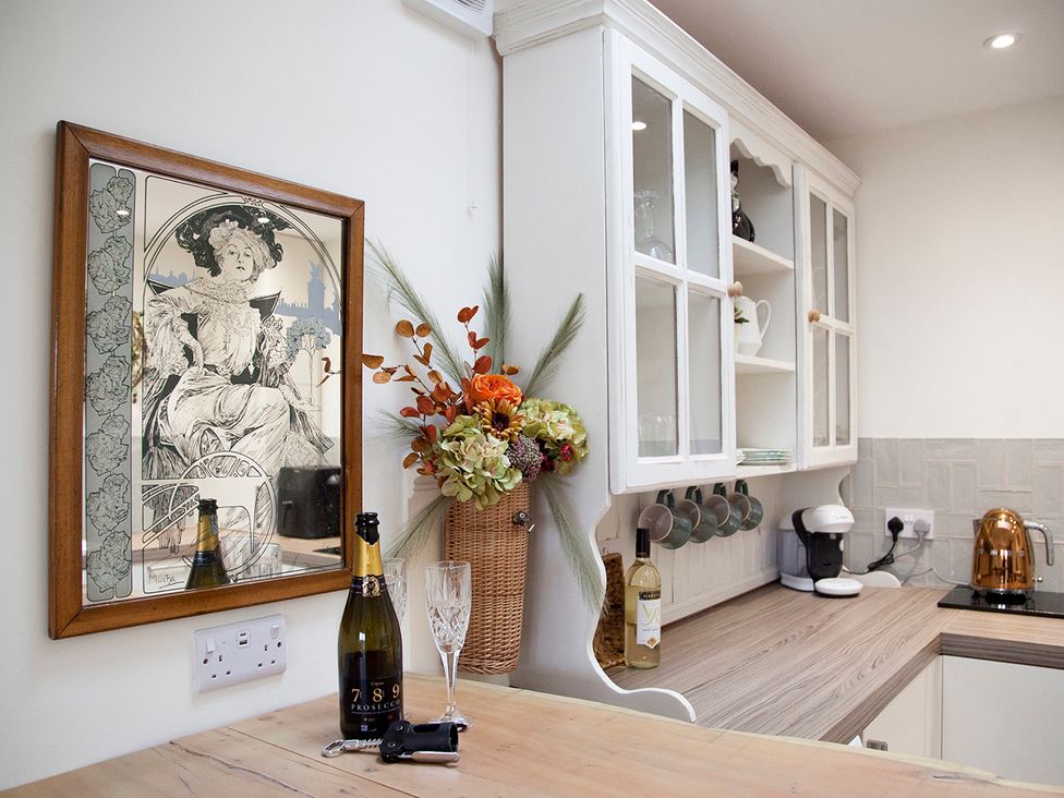 A kitchen with a champagne bottle and glasses at Snug Cottage in Honley