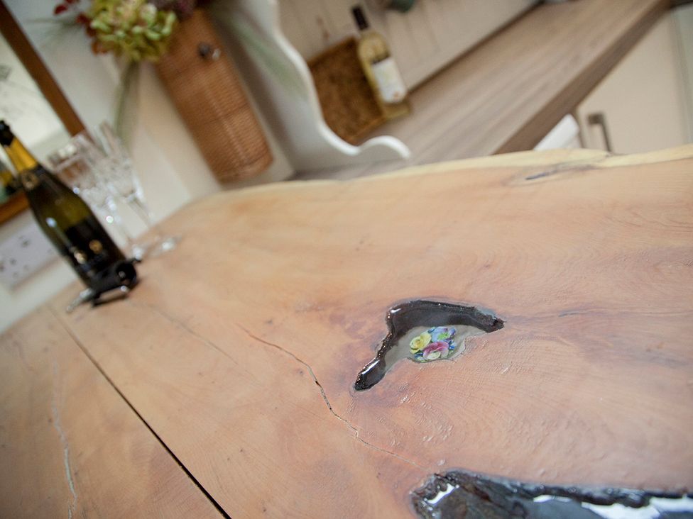 A wooden countertop with a champagne bottle and glasses at Snug Cottage in Honley