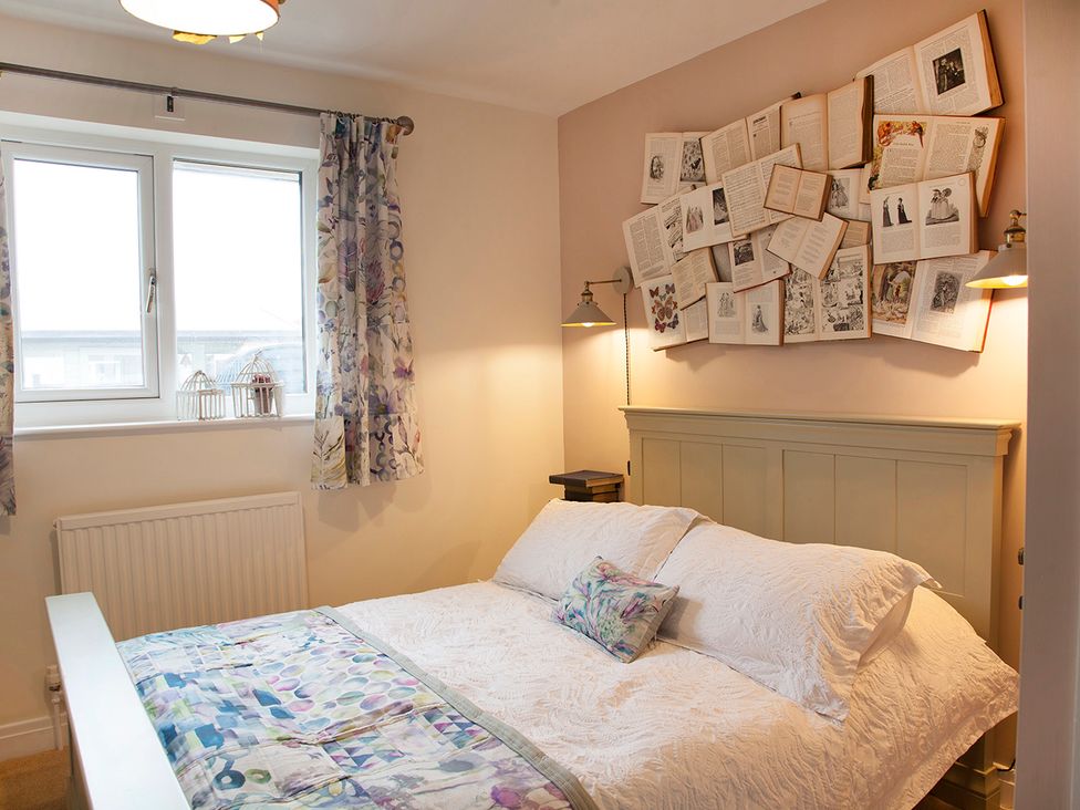A bedroom with a bed, lamp, and window at Snug Cottage in Honley