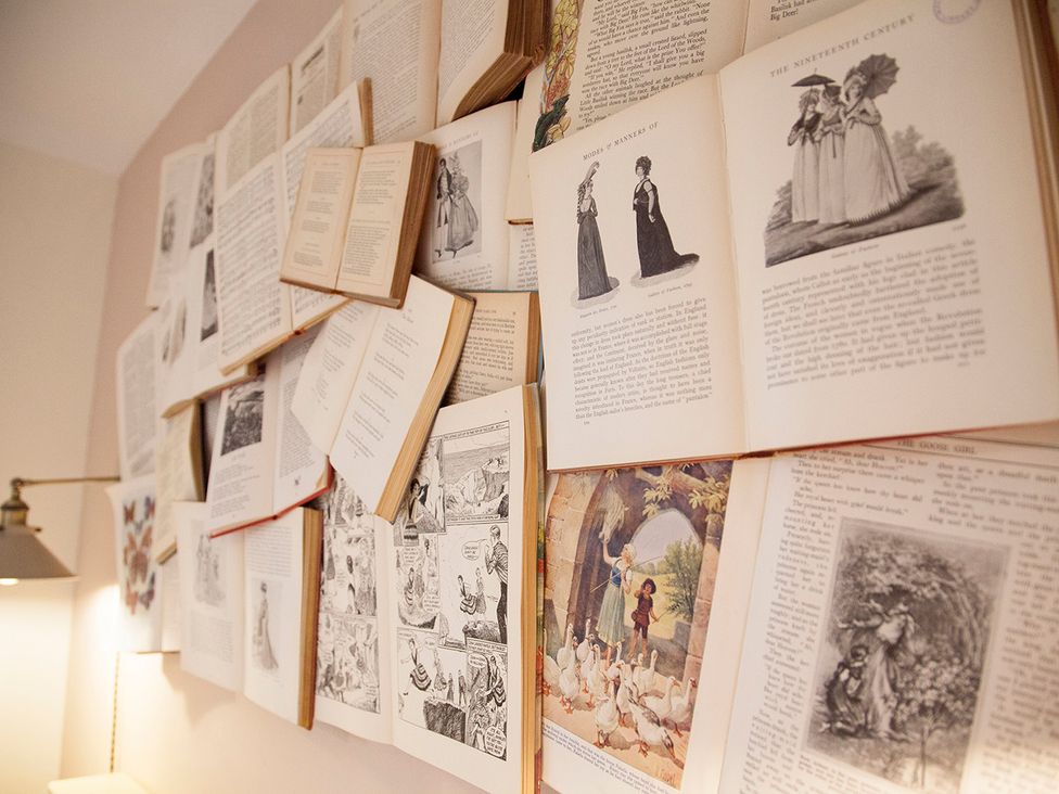A collection of opened books on a wall at Snug Cottage Honley
