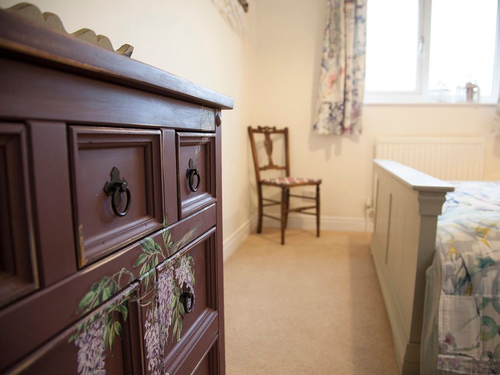 A bedroom with a chest of drawers and a chair at Snug Cottage Honley