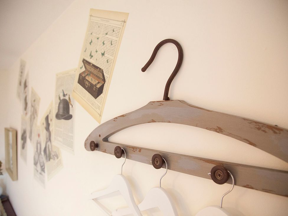 A wall with a hanger and decorative papers at Snug Cottage Honley