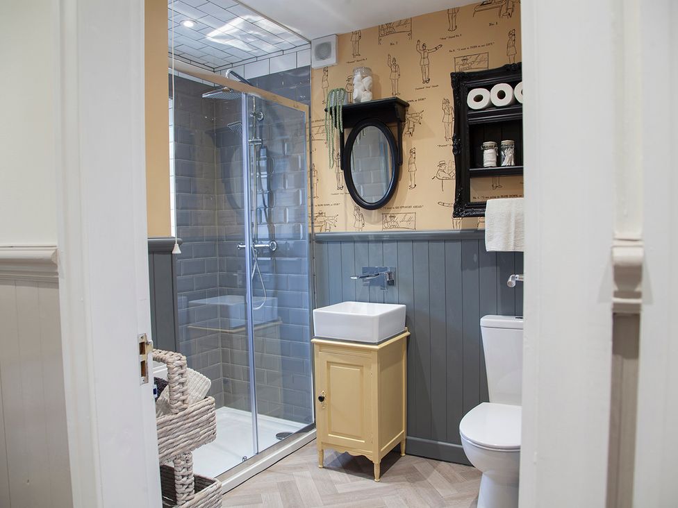 A bathroom with a shower, sink, and toilet at Snug Cottage in Honley