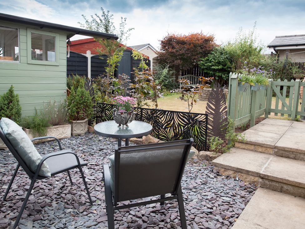 A garden with chairs and a table near a shed at Snug Corner in Honley