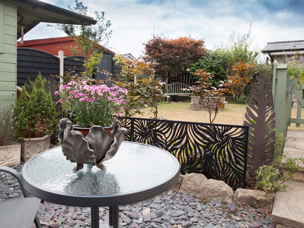 A garden with a table and flower pot at Snug Corner in Honley