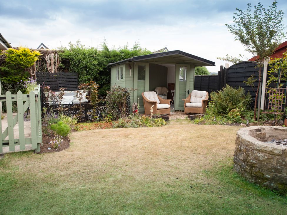 A garden with a shed and armchairs at Snug Corner in Honley