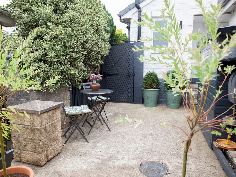 A garden with a table and chairs at Snug Corner in Honley