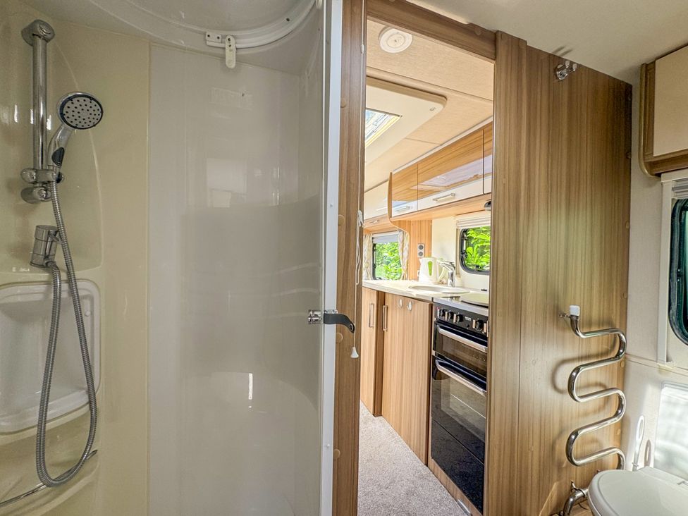 A bathroom with a shower and a view of the kitchen at Caravan Dolton
