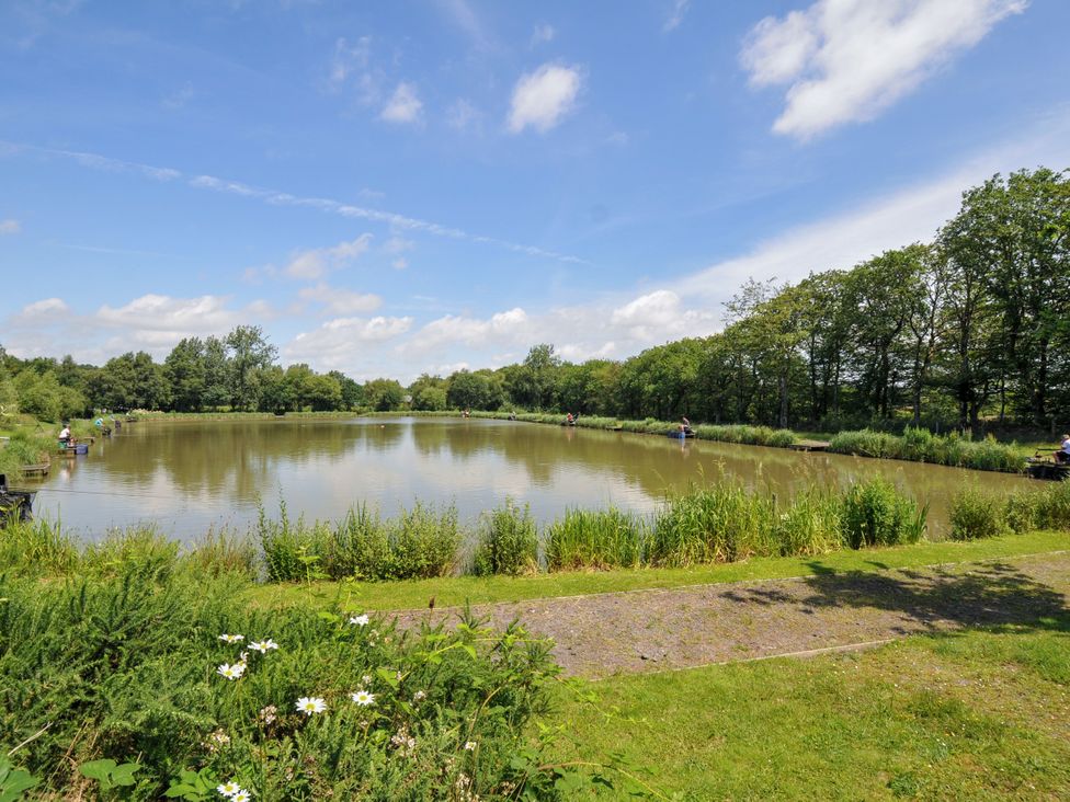 A pond with people fishing and greenery at Caravan in Dolton