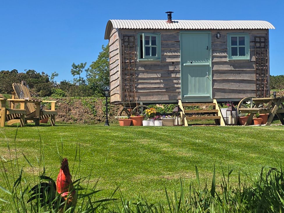 A wooden cabin with steps and garden furniture at Cwt Bugail in Pwllheli