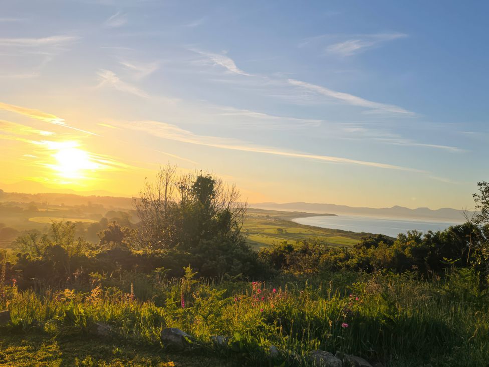 A sunset view over water with plants at Cwt Bugail Pwllheli