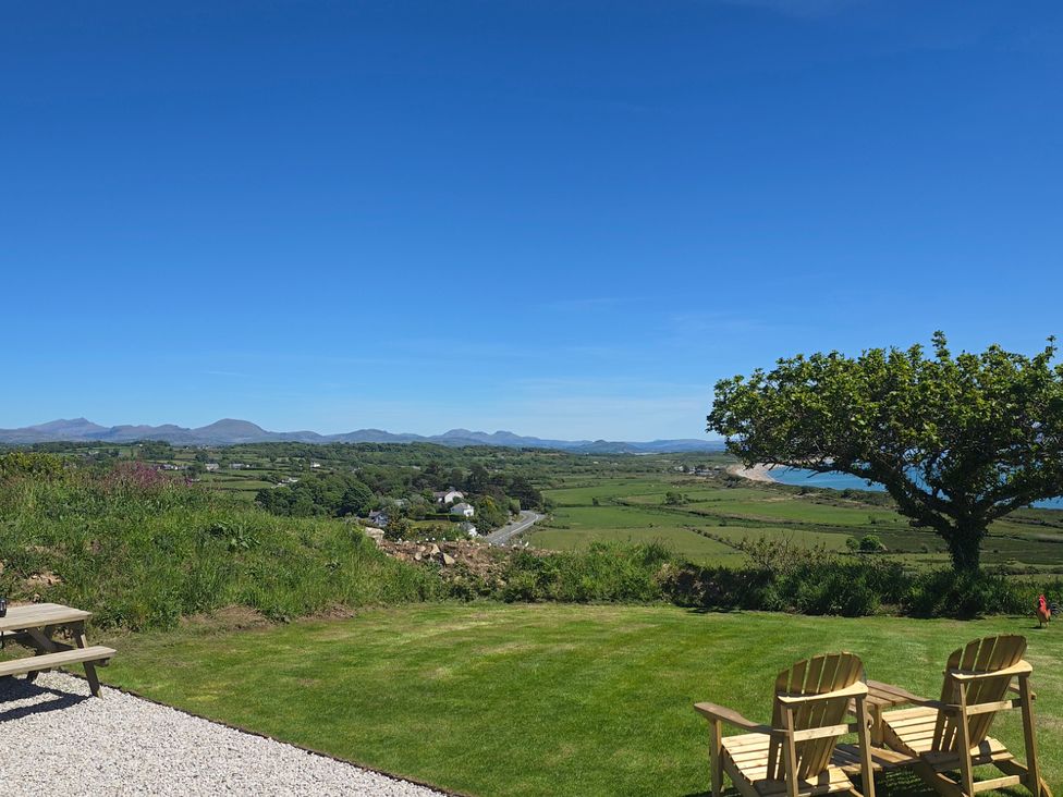 A garden with chairs and a view of mountains at Cwt Bugail in Pwllheli