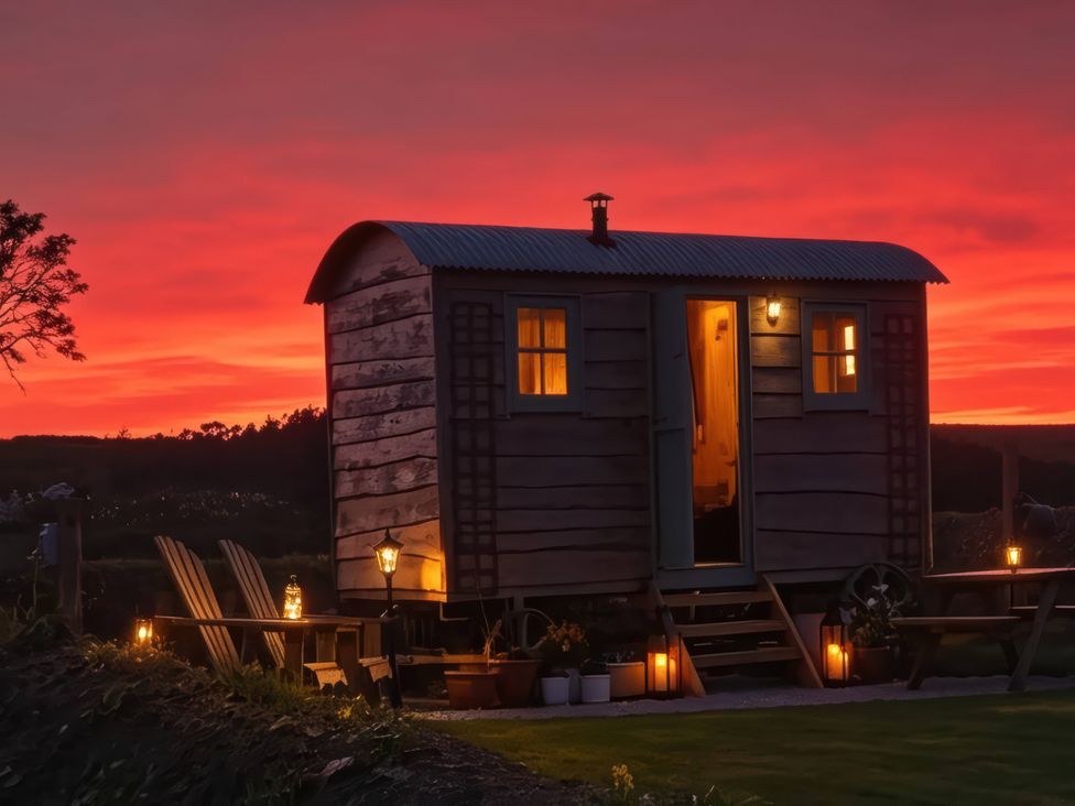 A wooden cabin with light fixtures and chairs at Cwt Bugail Pwllheli