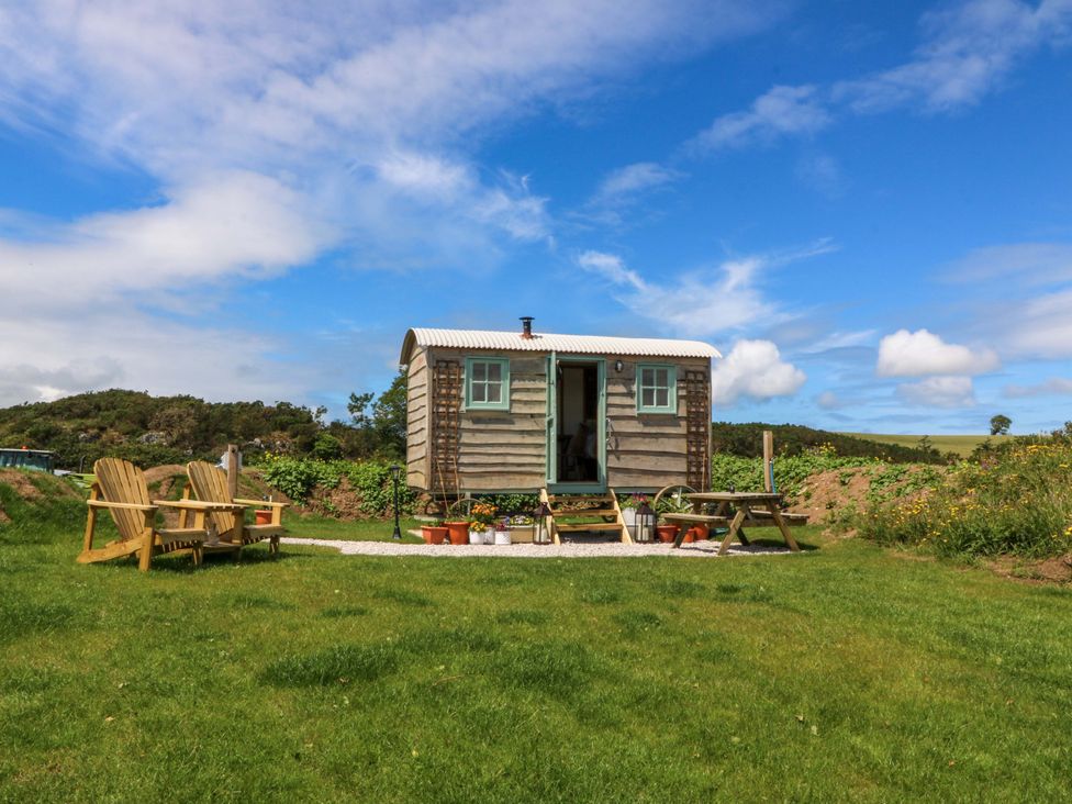 An outdoor cabin with a door and chairs at Cwt Bugail Pwllheli