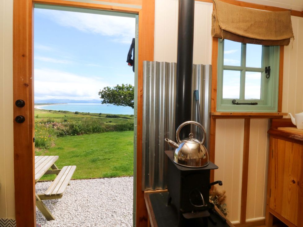 A kitchen with a kettle on a stove and view of the sea at Cwt Bugail in Pwllheli