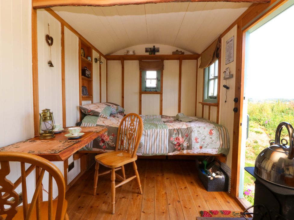 A bedroom with a bed and a small table at Cwt Bugail in Pwllheli