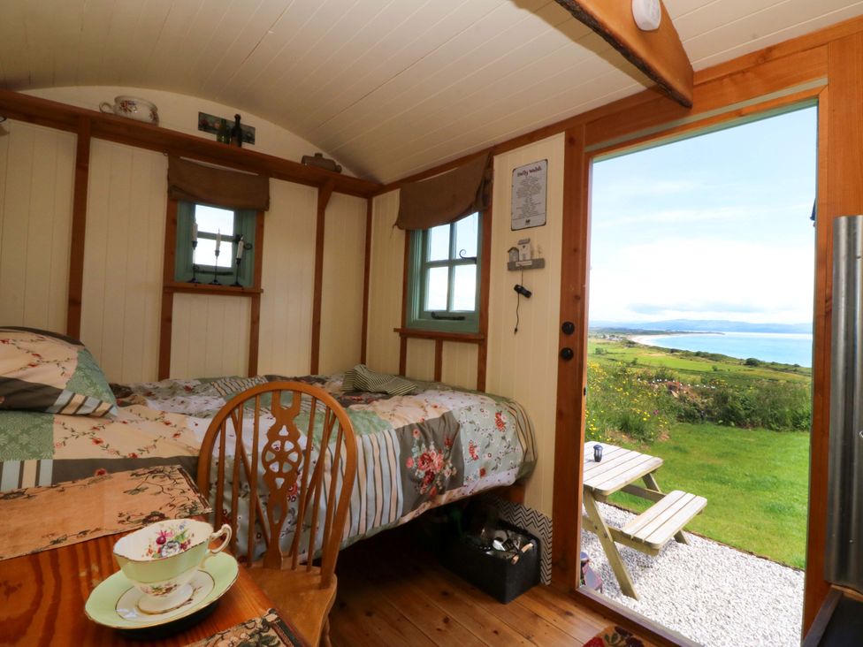 A bedroom with a bed and table at Cwt Bugail in Pwllheli