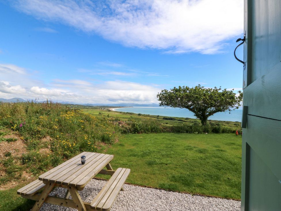 A table on grass with a view of the ocean at Cwt Bugail Pwllheli