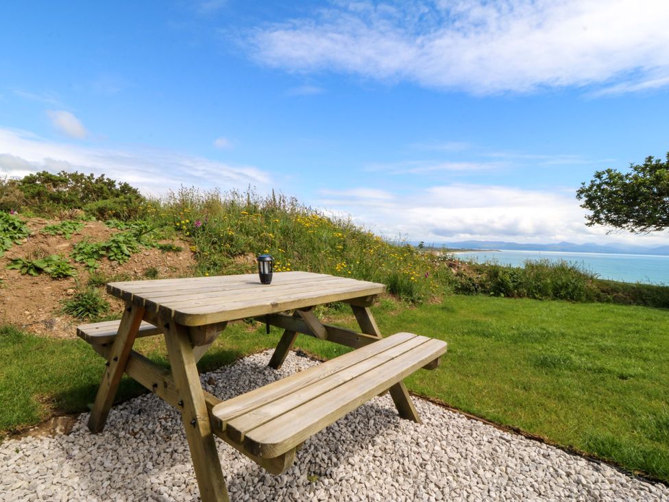 A picnic table on grass with a cup at Cwt Bugail Pwllheli