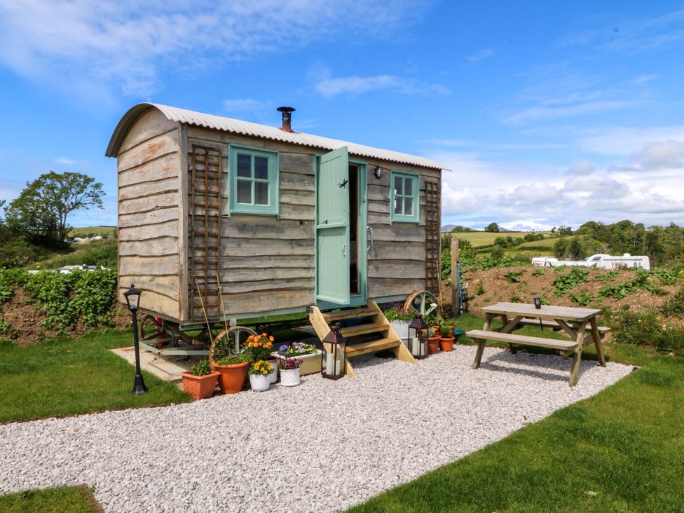 A wooden hut with steps and lamp near a picnic table at Cwt Bugail Pwllheli
