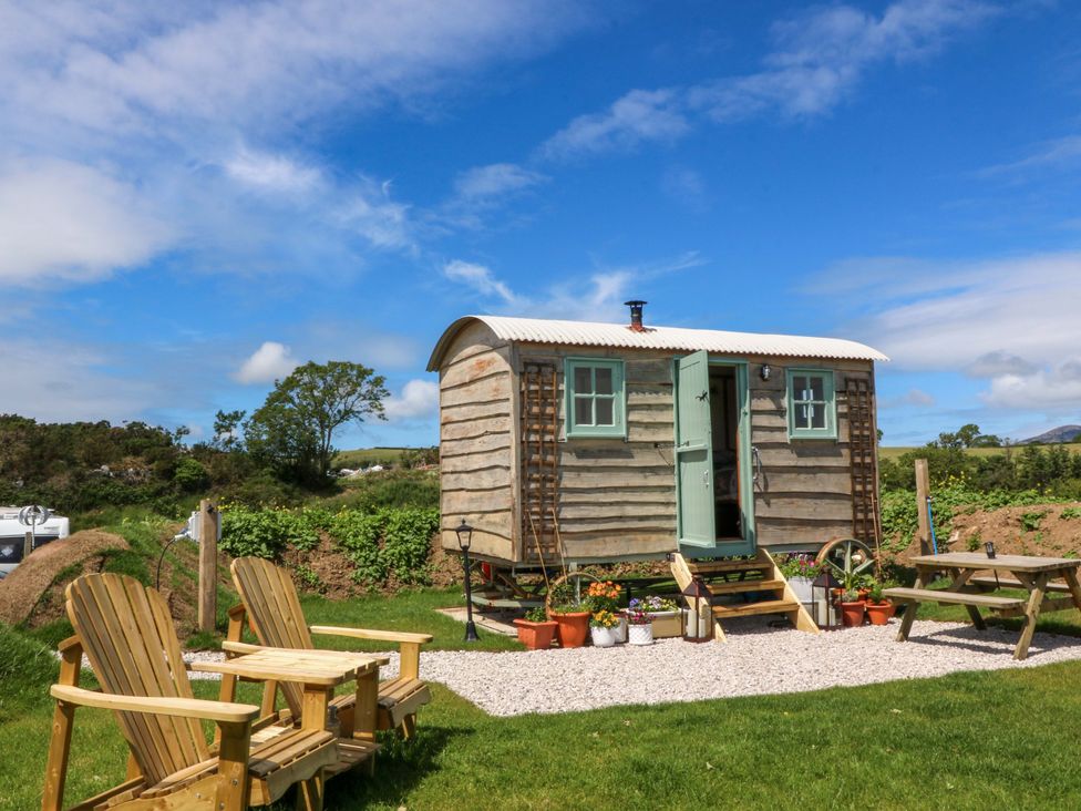 A shepherd's hut with seating area outside at Cwt Bugail in Pwllheli