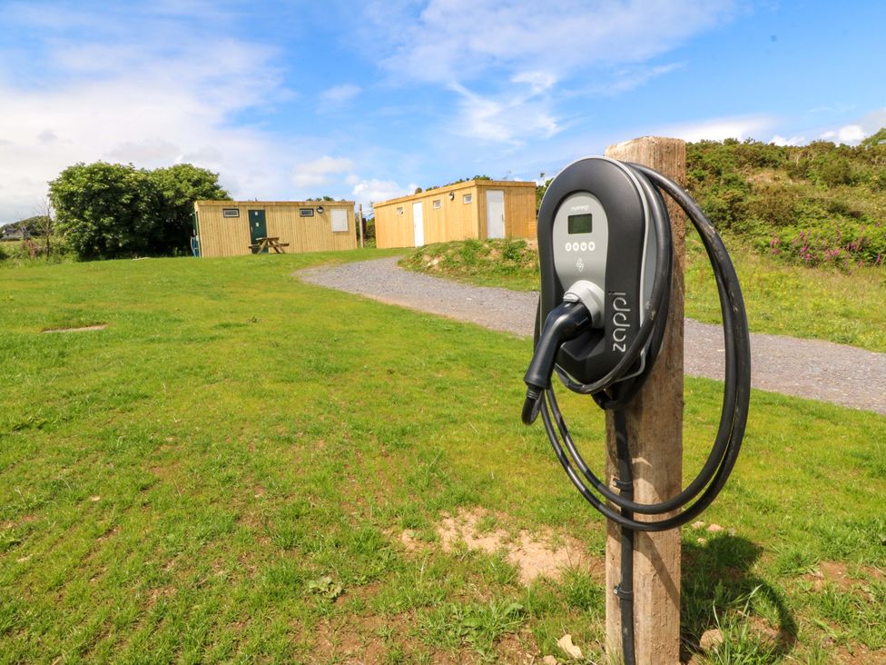 An electric vehicle charger in a grassy outdoor area at Cwt Bugail in Pwllheli
