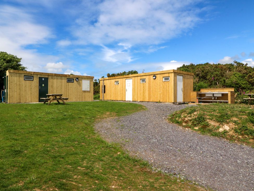 Wooden buildings and a picnic table in an outdoor area at Cwt Bugail, Pwllheli