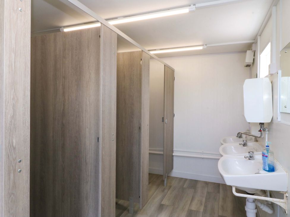 A bathroom with toilet stalls and sinks at Cwt Bugail Pwllheli