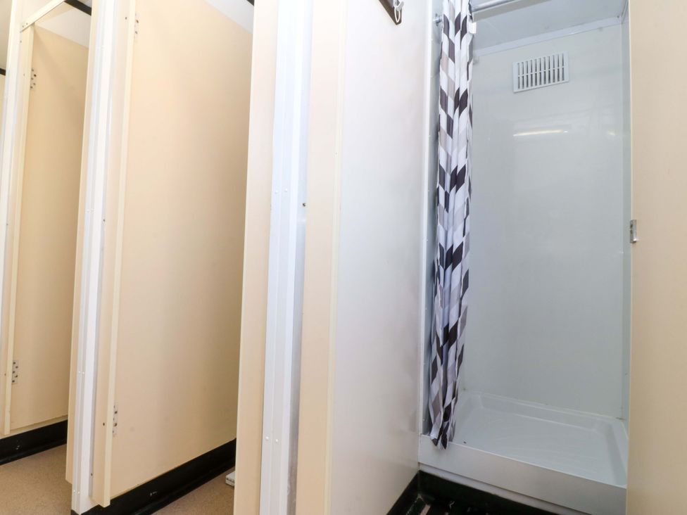 A shower with a curtain in a bathroom at Cwt Bugail in Pwllheli