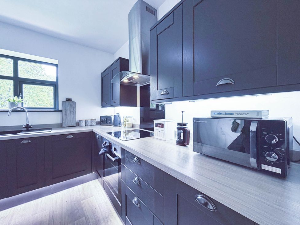 A kitchen with dark cabinets and appliances at Stunning Retreat in the Heart of Matlock Bath near Matlock