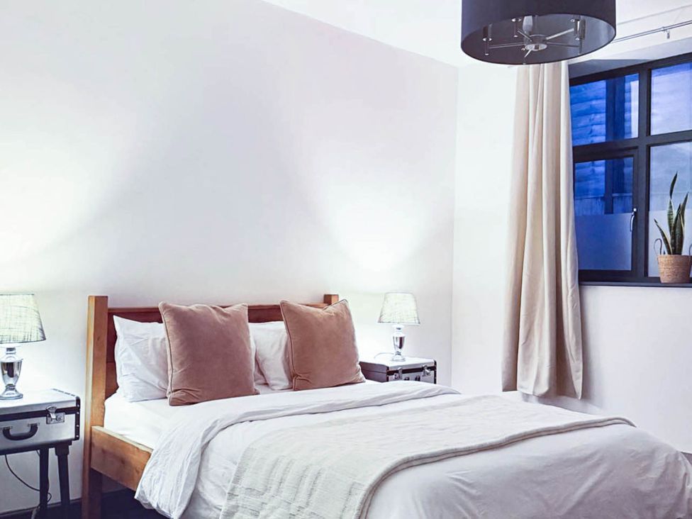 A bedroom with a bed, nightstand, and window at Stunning Retreat in the Heart of Matlock Bath