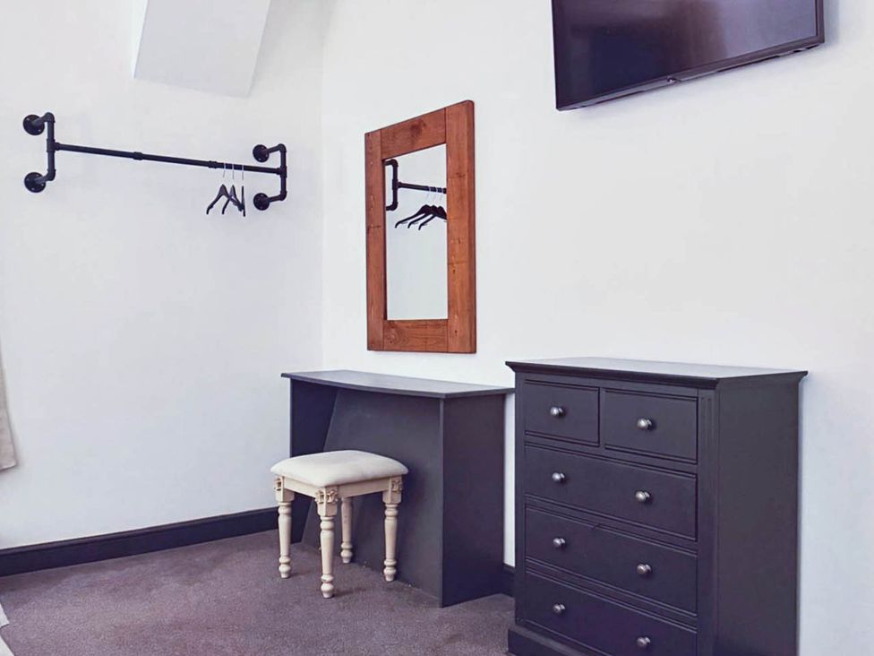 A bedroom with a mirror, dresser, chair, and television at Stunning Retreat in the Heart of Matlock Bath