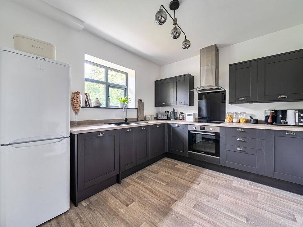 A kitchen with dark cabinets and appliances at Stunning Retreat in the Heart of Matlock Bath, Matlock Bath near Matlock