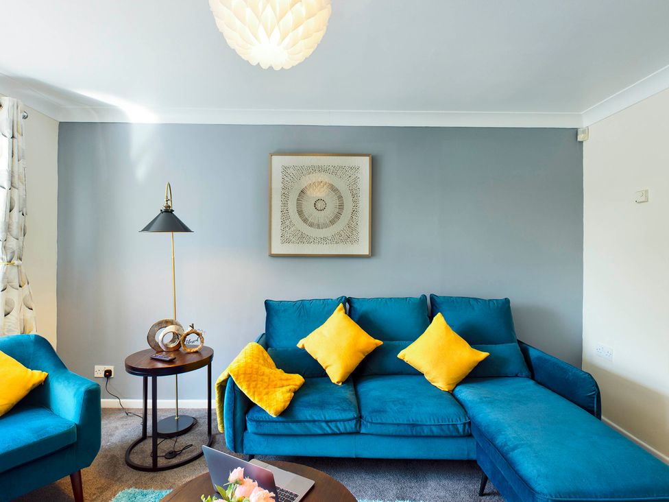 A living room with a blue sofa and yellow cushions at Tranquil Telford Retreat - 3 Bedroom House Telford