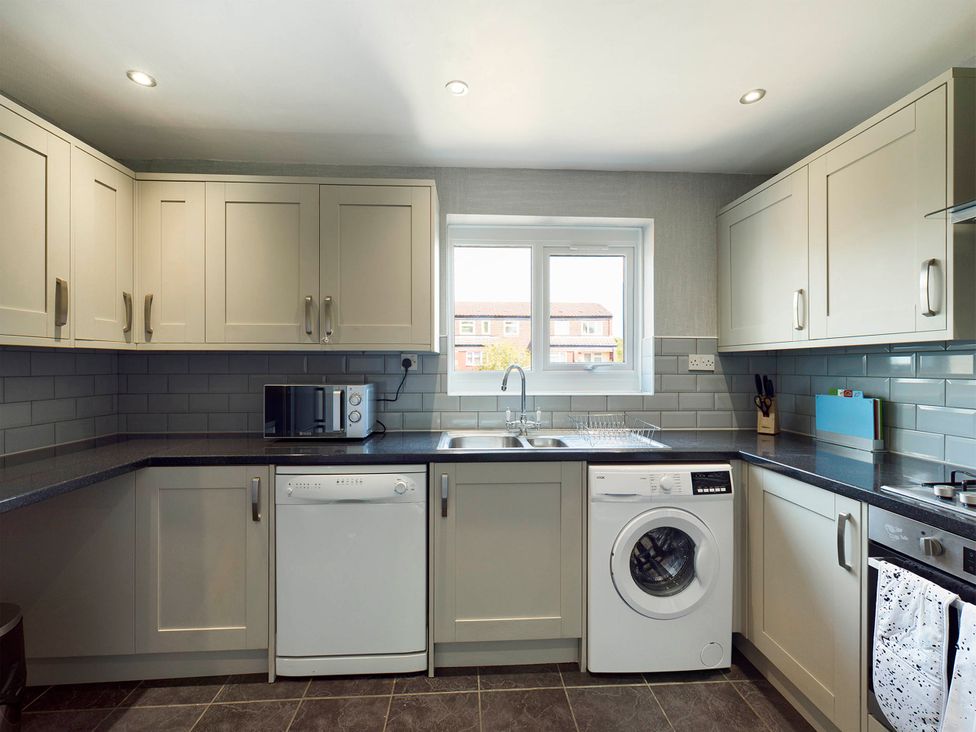 A kitchen with appliances including a washing machine and microwave at Tranquil Telford Retreat - 3 Bedroom House Telford