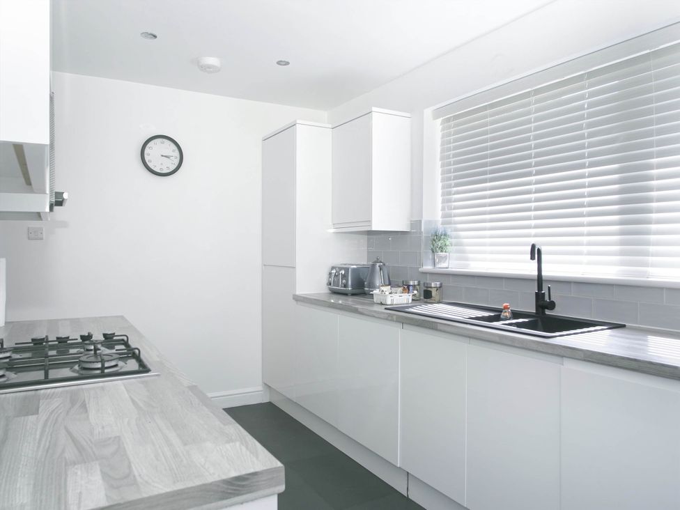 A kitchen with a gas stove and sink at Cozy Riverside Retreat in Snodland