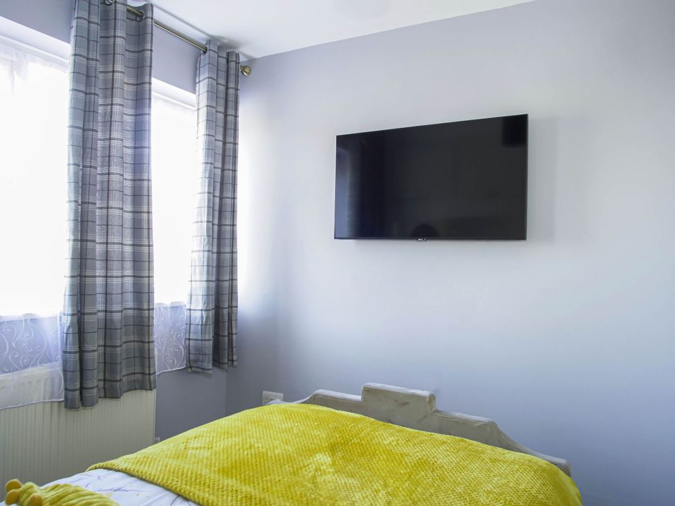 A bedroom with a television on the wall at Cozy Riverside Retreat in Snodland