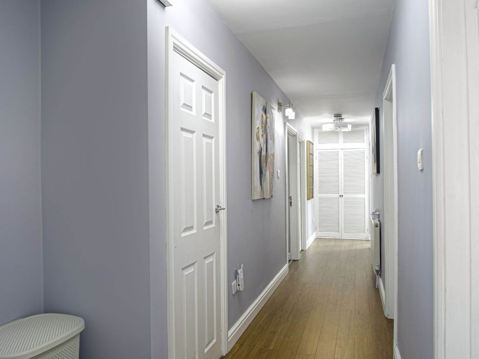 A hallway with multiple doors and an artwork at Cozy Riverside Retreat in Snodland