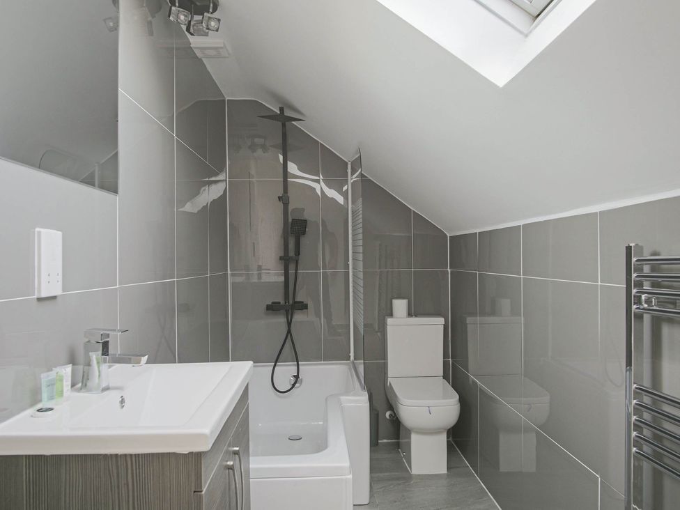 A bathroom with a bathtub, shower, toilet, and sink at Cozy Riverside Retreat in Snodland