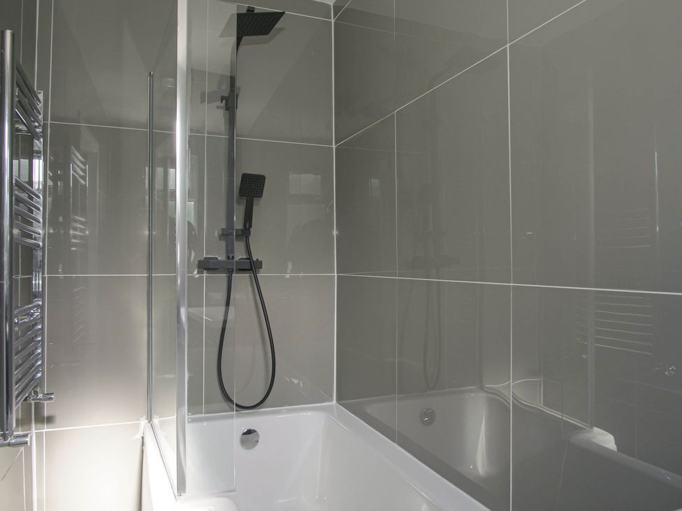 A bathroom with a bathtub and showerhead at Cozy Riverside Retreat in Snodland