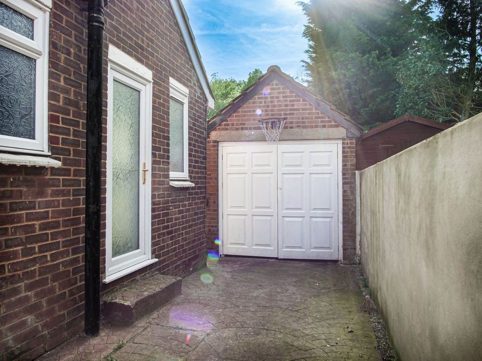 An outdoor area with a garage door and a basketball hoop at Cozy Riverside Retreat in Snodland