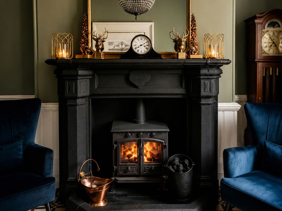 A fireplace with a clock and armchairs in a living room at Chowdene Lodge Estate