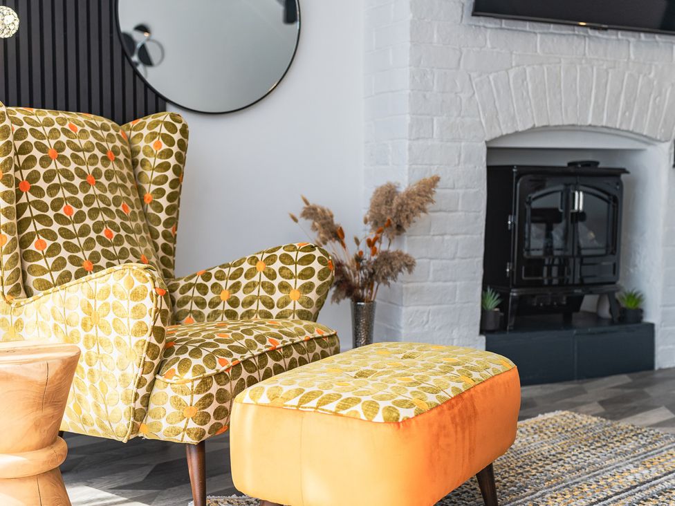 A living room with an armchair and ottoman near a fireplace at The Old Barn in Manchester