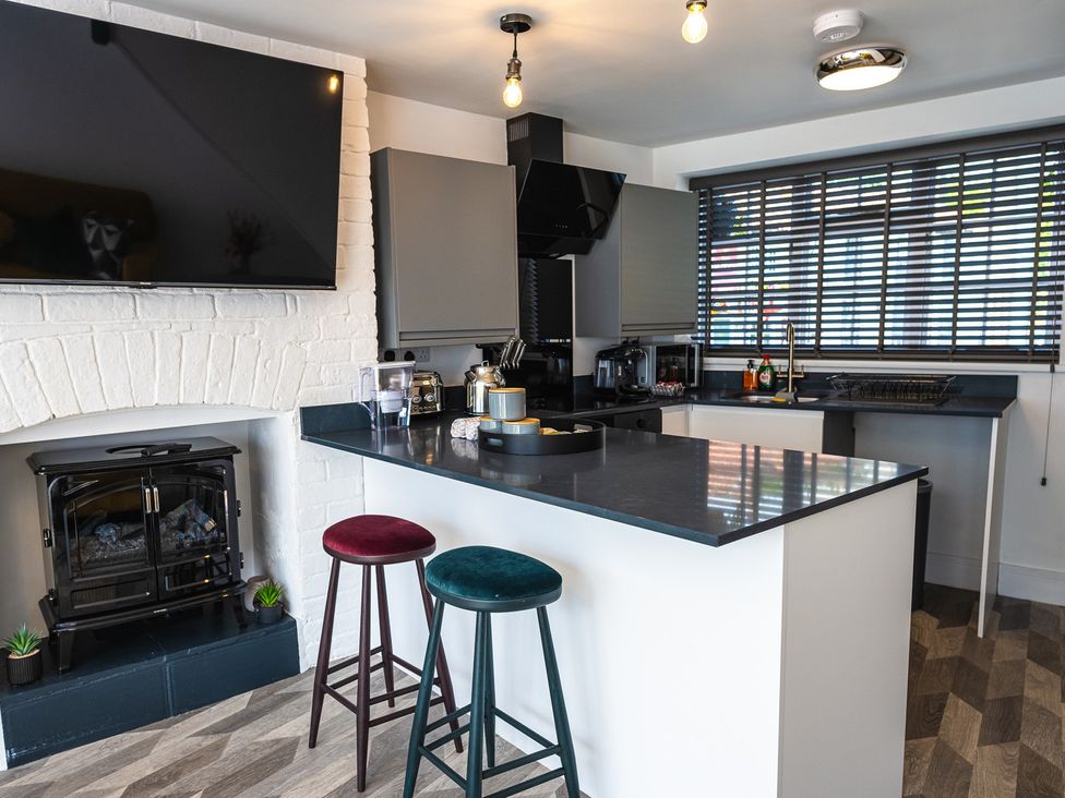 A kitchen with a countertop, stools, and appliances at The Old Barn in Manchester
