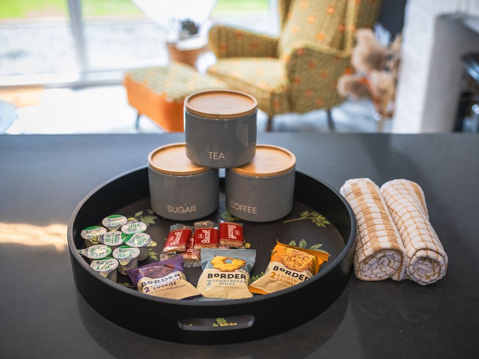 A tray with tea, sugar, coffee containers and snacks in a kitchen