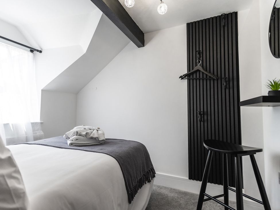A bedroom with a bed, towels, and a wall shelf at The Old Barn in Manchester
