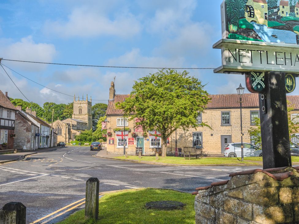 A view of a village street with a church and buildings at Nettleham in Nettleham